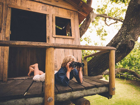 Kid in treehouse using binoculars PP stock photo